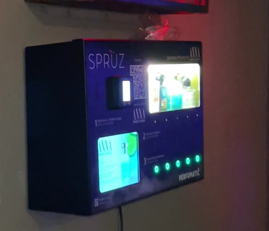 Dettaglio della macchina Sprùz a parete: display delle fragranze, lettore contactless e pulsanti illuminati